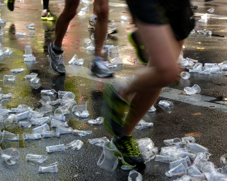 Marathonläufer rennen durch Plastikbecher an Wasserausgabestelle