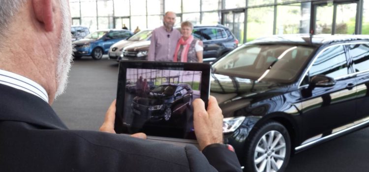 Ehepaar posiert für Foto beim Abholen seines neuen Autos im Kundenzentrum von VW