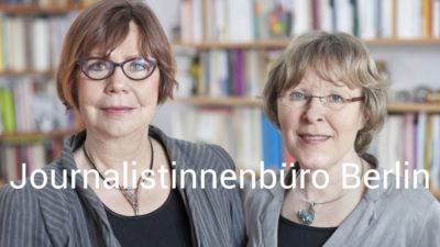 Zwei Frauen schauen in die Kamera, dahinter Bücherwand