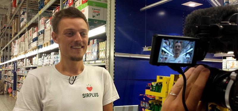 Mann im T-Shirt mit Logo SirPlus steht vor der Kamera im MetroMarkt